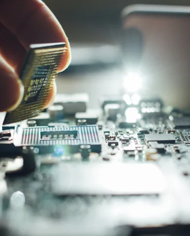 Mão posicionando um microchip sobre uma placa de circuito impresso