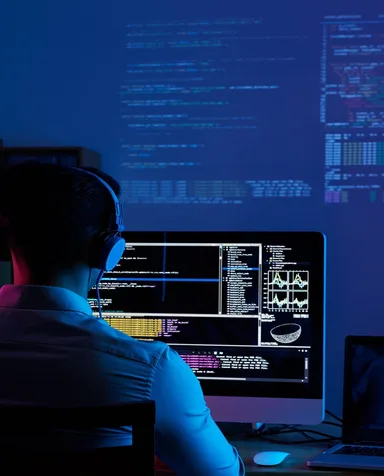 Profissional diante de monitores com código e painéis de acompanhamento de testes